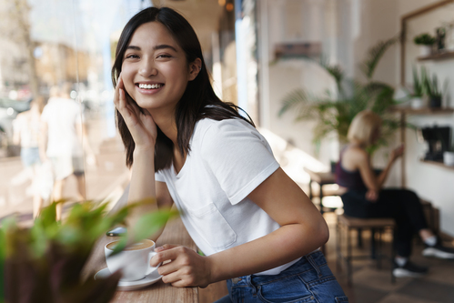 happy asian woman sitting restaurant near window smiling camera 1